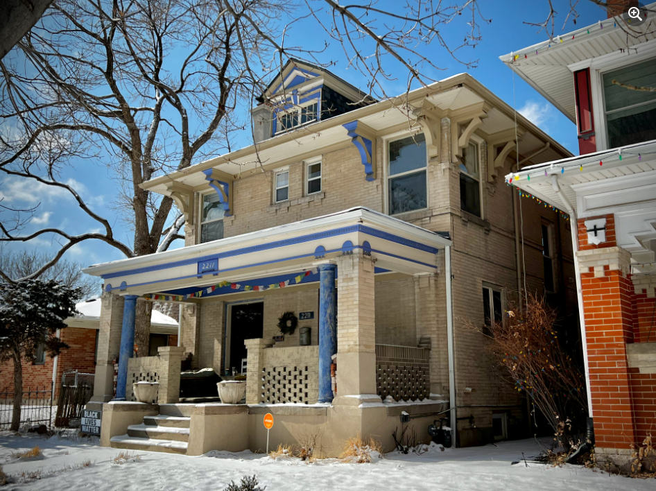 a house covered in snow in front of a building