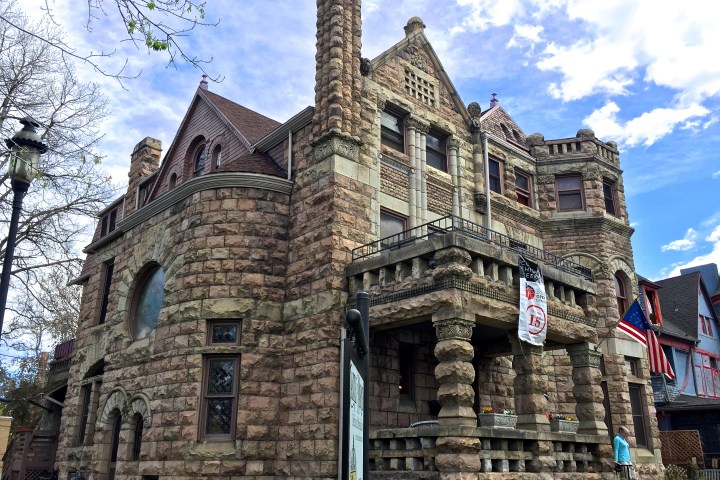 Historic stone mansion with turrets and balconies, under a blue sky.