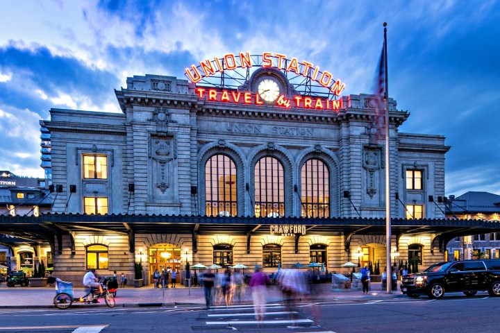 a large building with a clock on the side of a road with Union Station in the background
