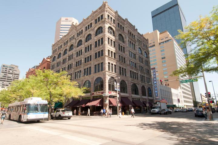 a group of people walking down a street next to tall buildings