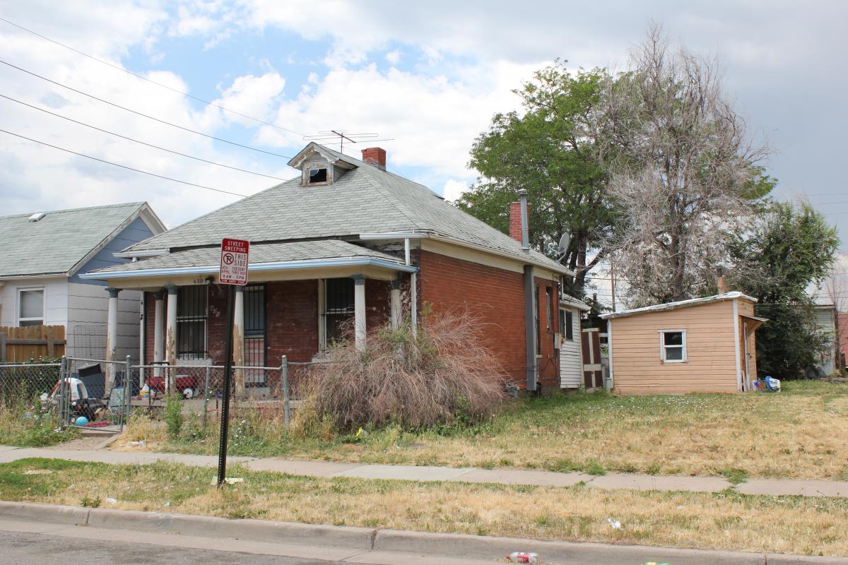 a house that has a sign on the side of a road