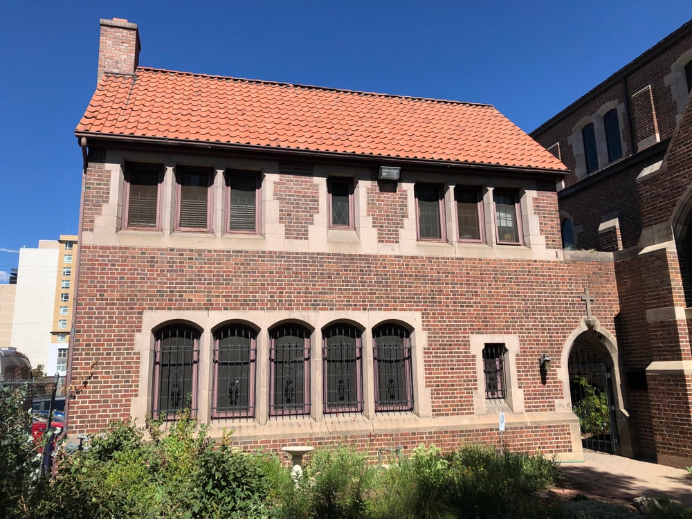 Brick building with arched windows and red tile roof on a sunny day.