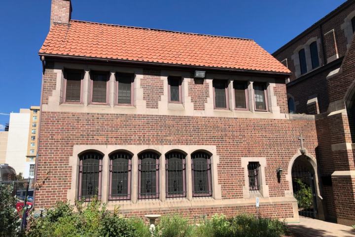 Brick building with arched windows and red tile roof on a sunny day.