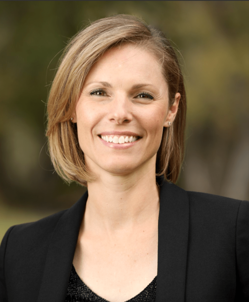 a person wearing a suit and tie smiling at the camera