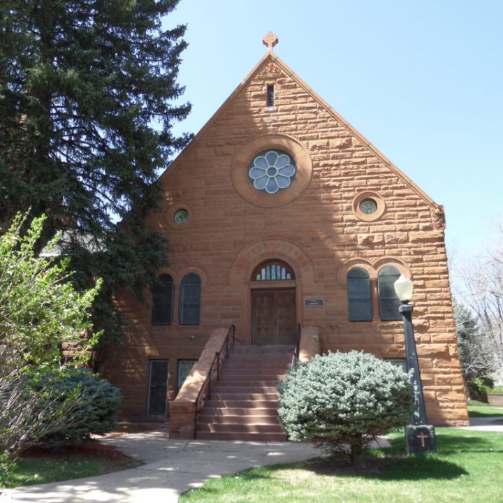 a small clock tower in front of a brick building