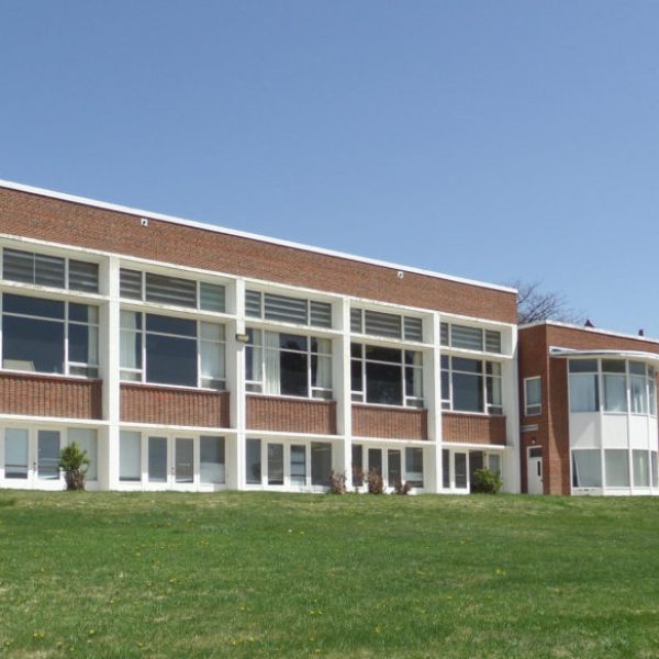 a large brick building with grass in front of a house