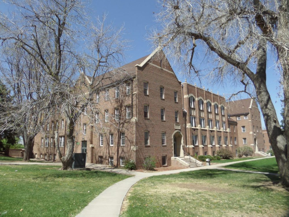 a large brick building with grass and trees