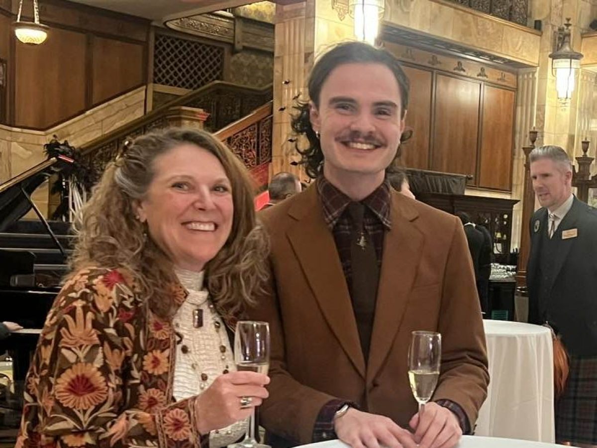 Two people smiling and holding champagne glasses at a formal event.