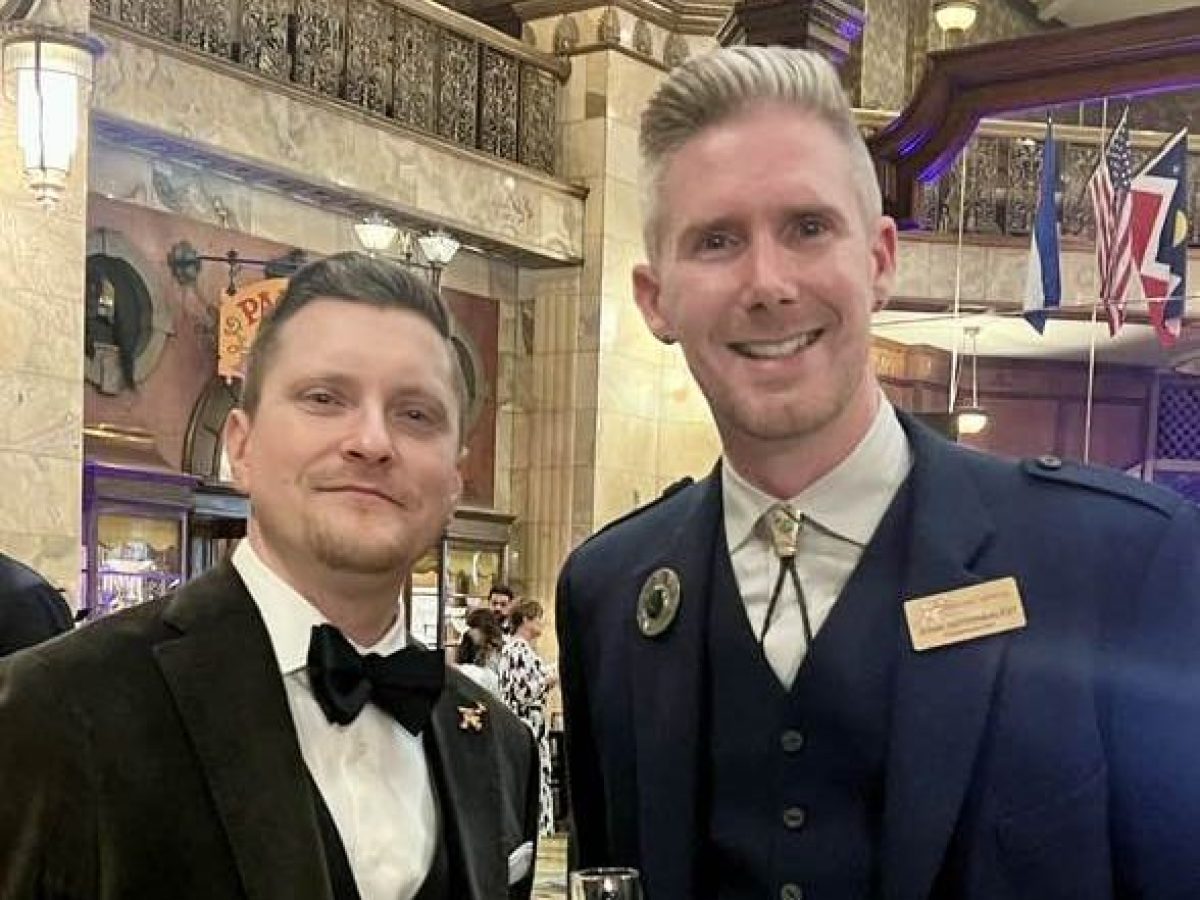 Two men in formal attire at an indoor event, one wearing a kilt with a decorative sporran.