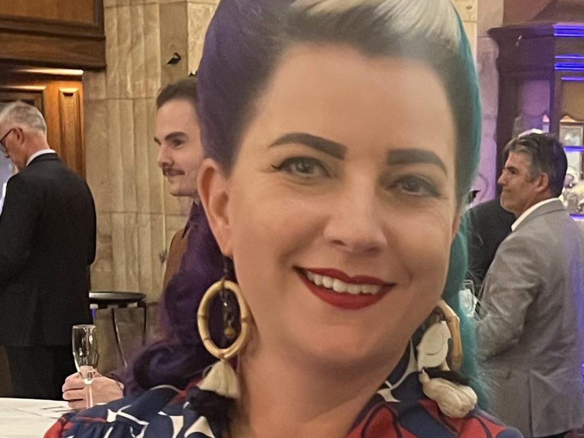 Woman with retro hairstyle and geometric patterned dress at a formal event.