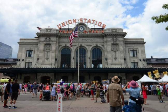 Crowd at Union Station with American flag and clock on a sunny day.