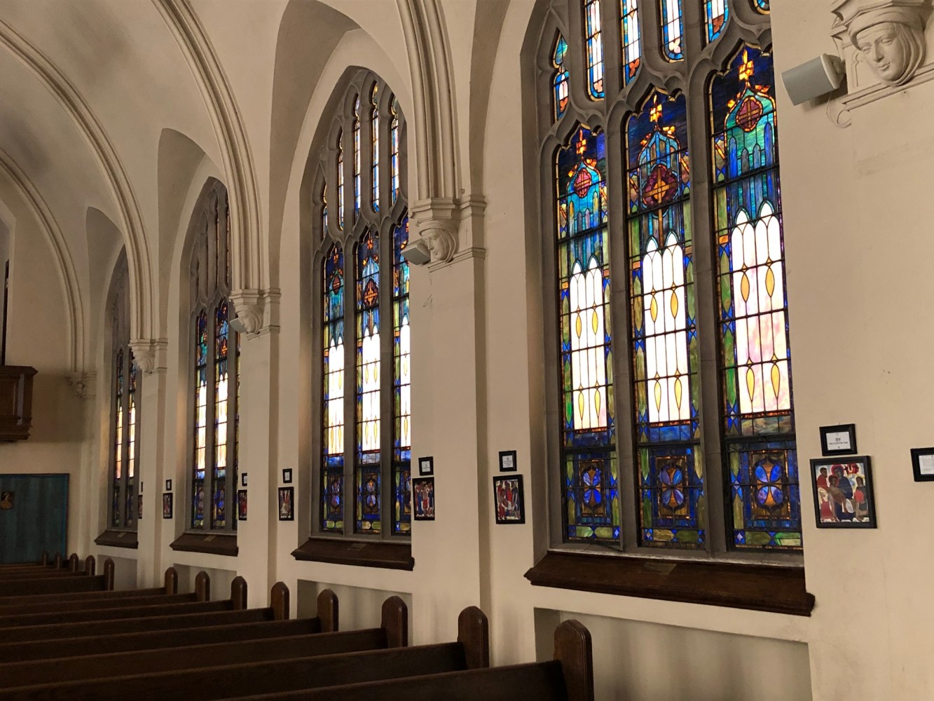 Interior of a church with stained glass windows and wooden pews.