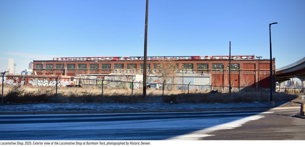 Large brick industrial building with graffiti under a clear sky.