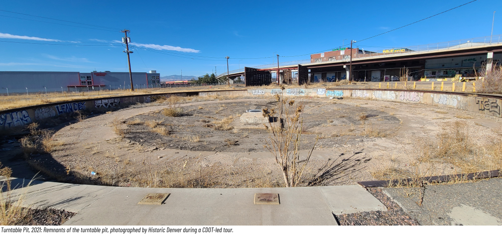 Abandoned, graffiti-covered roundabout with dry grass under a clear sky.