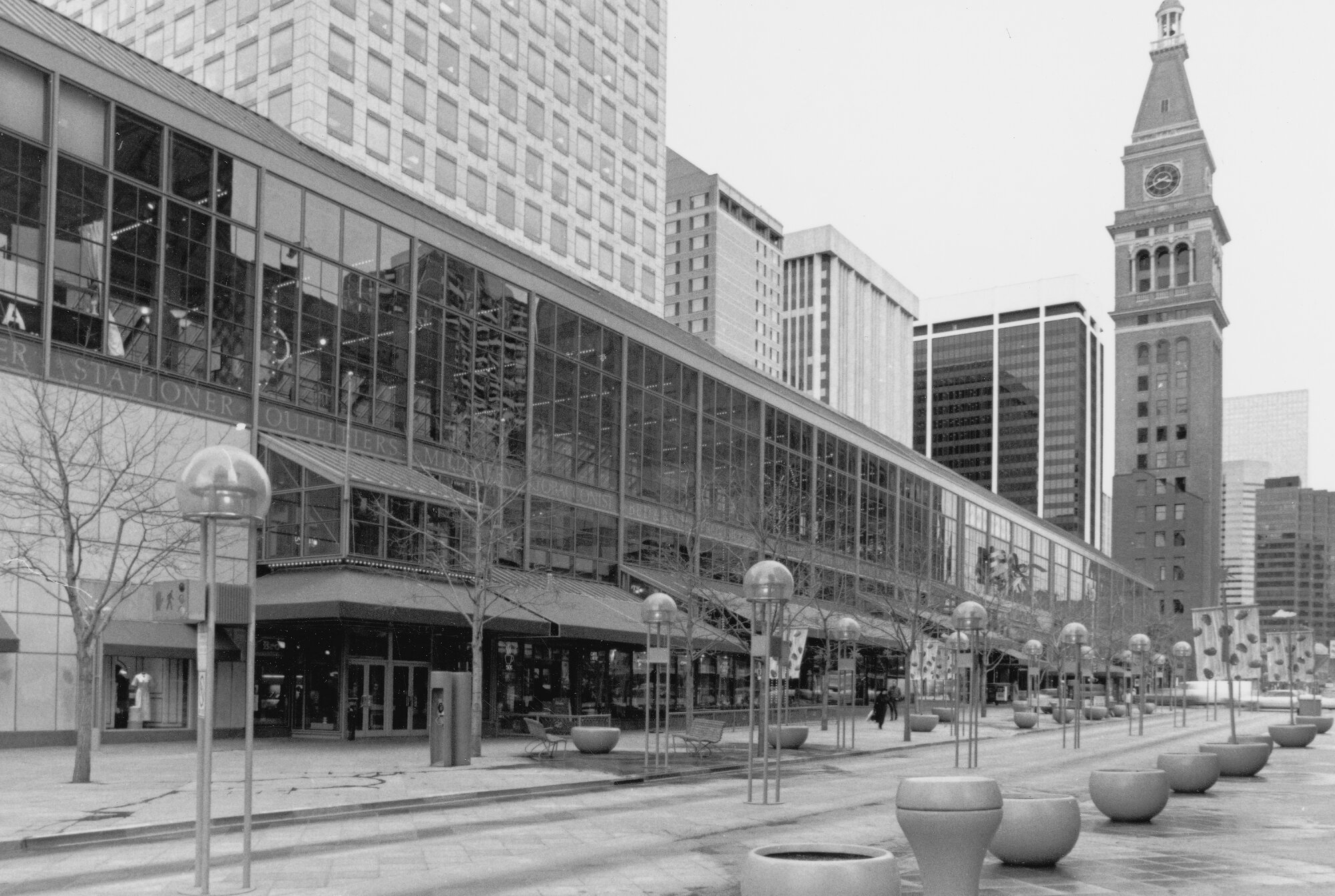 Black and white photo of a city street with a clock tower and modern buildings.