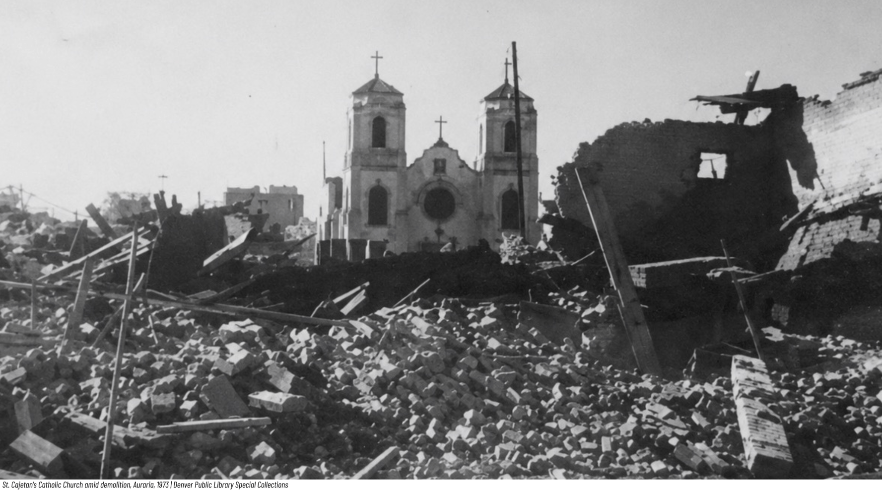Rubble surrounds a damaged church with twin towers in the background.